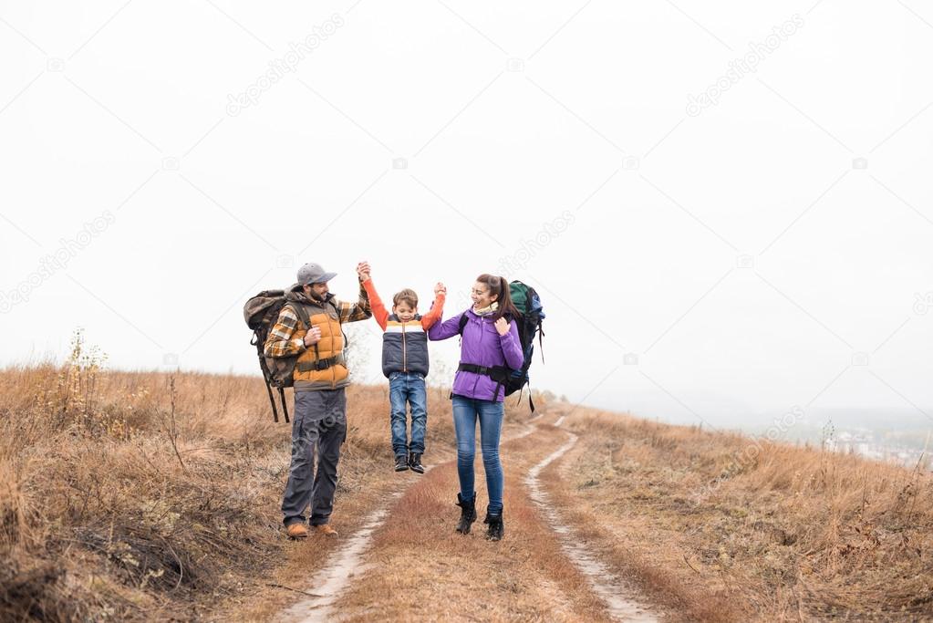 Happy family with backpacks holding hands