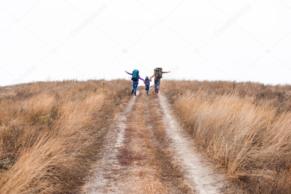Family with backpacks running on rural path