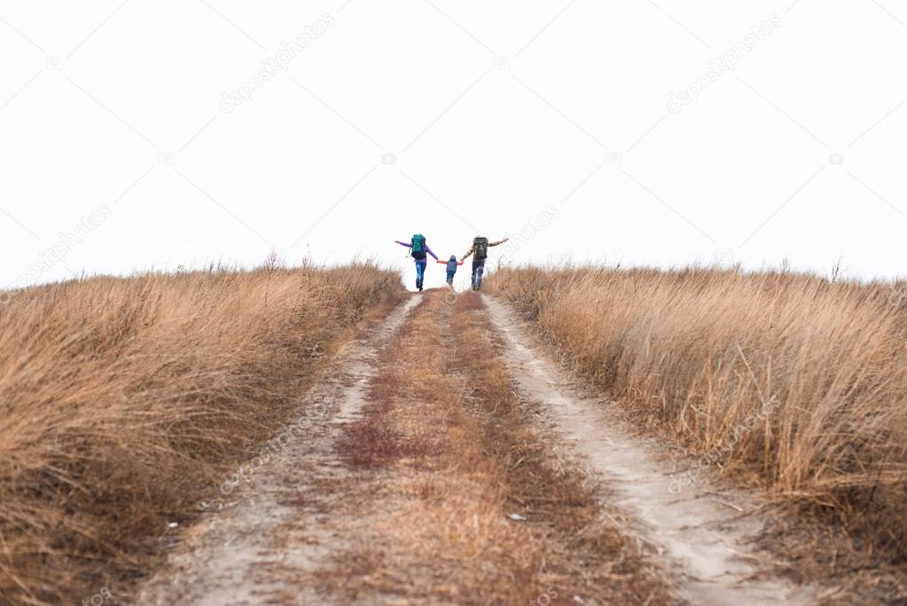 Family with backpacks running on rural path