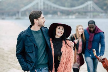 Young people having stroll on beach clipart