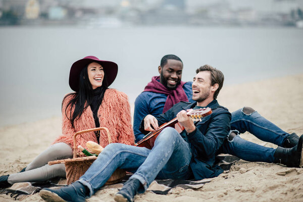 Happy friends with guitar at picnic