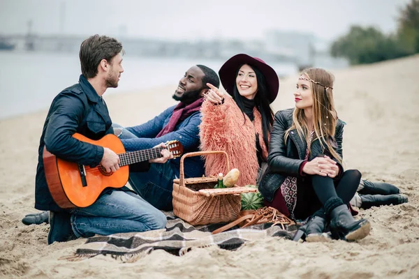 Happy mladí přátelé s kytarou na pikniku — Stock fotografie