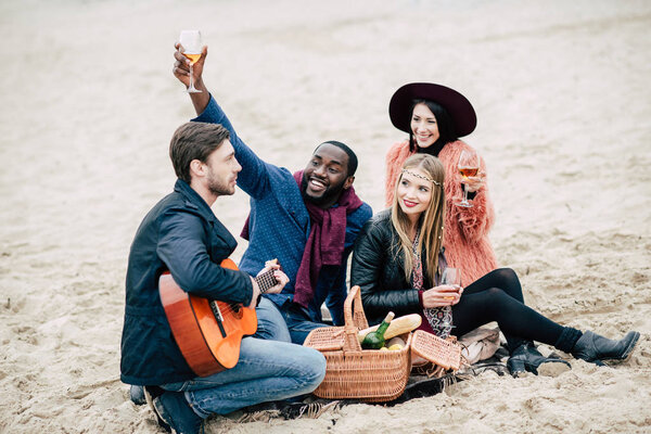Счастливые молодые друзья с гитарой на пикнике
