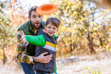 Smiling father and son playing with frisbee clipart