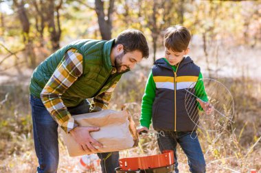 Baba ve oğul kömür ızgara koyarak 