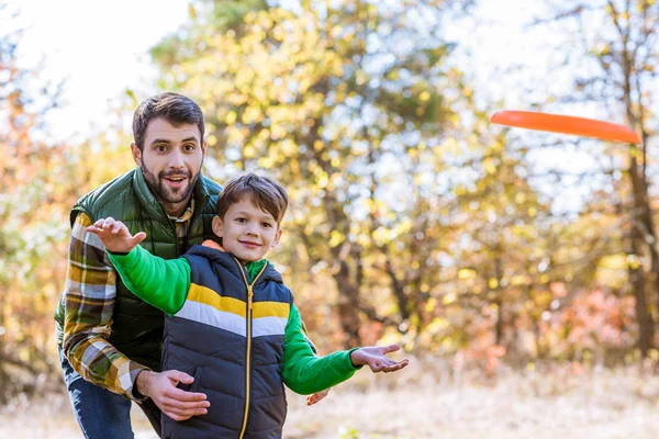 Lachende vader en zoon spelen met frisbee — Stockfoto