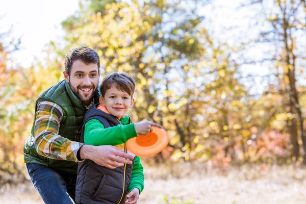 Leende far och son leker med frisbee — Stockfoto