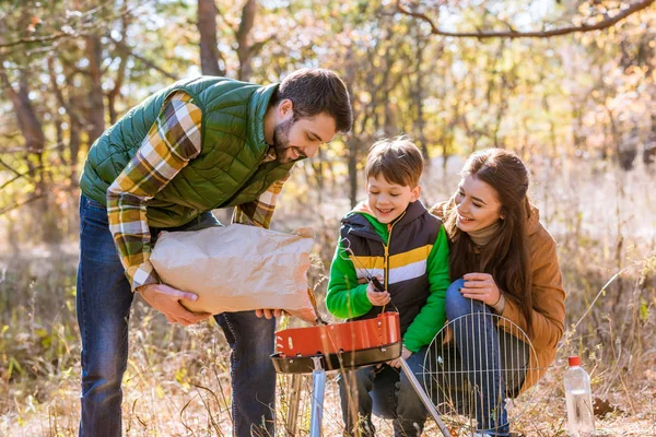 Padre e hijo poniendo brasas en la parrilla — Foto de Stock