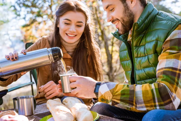 Lachende vrouw gieten thee thermoskannen — Stockfoto