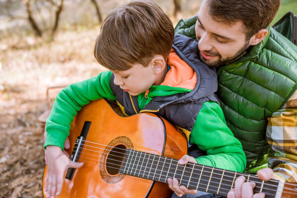 Father teaching son playing guitar