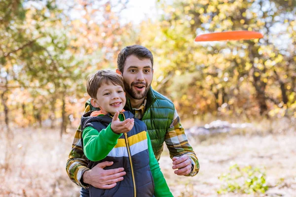 Lächelnder Vater und Sohn spielen mit Frisbee Stockfoto