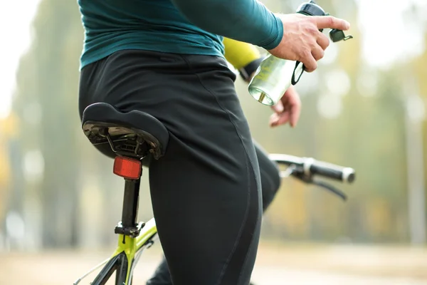 Cyclist holding bottle of water — Stock Photo