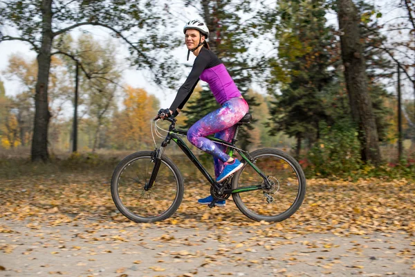 Mujer ciclismo en el parque de otoño - foto de stock