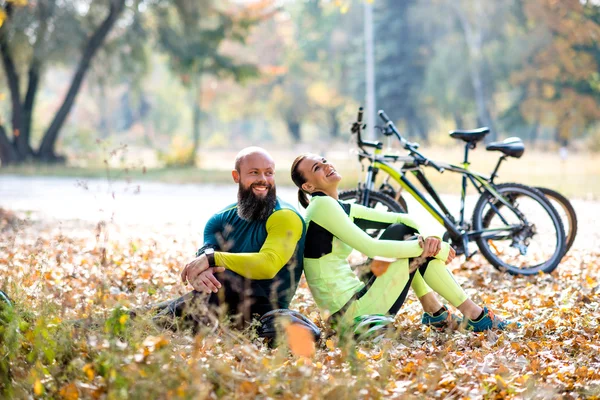 Ciclistas descansando en el césped seco de otoño - foto de stock