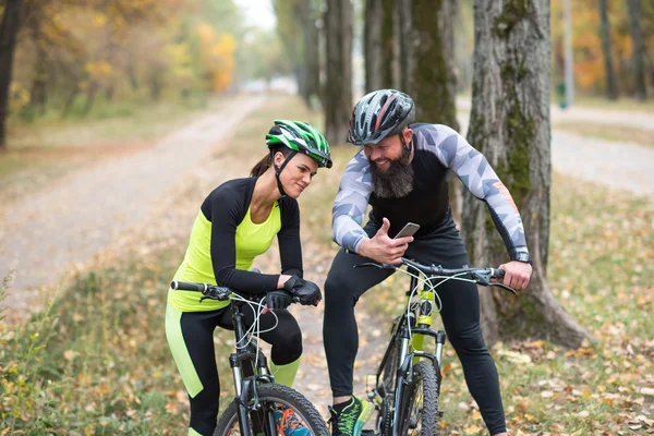 Man cyclist showin smartphone to girl — Stock Photo