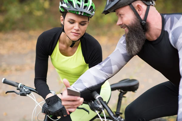 Man cyclist showin smartphone to girl — Stock Photo