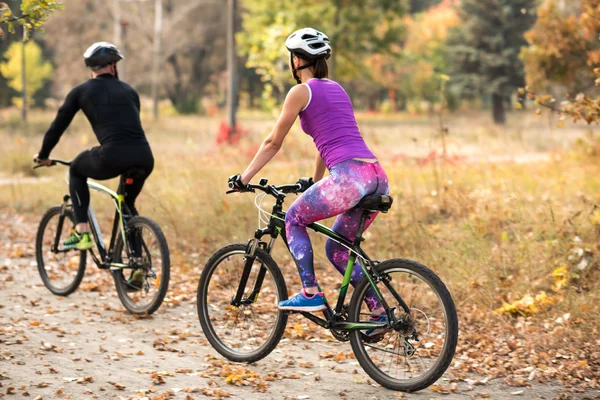 Люди катаются на велосипеде в осеннем парке — стоковое фото