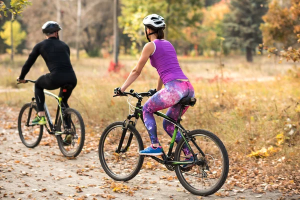 Persone in bicicletta nel parco autunnale — Foto stock