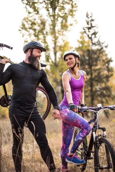 Un par de ciclistas sonrientes en el parque - foto de stock