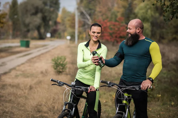 Pareja de ciclistas descansando en el parque - foto de stock