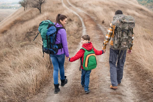 Family with backpacks walking on rural path — Stock Photo
