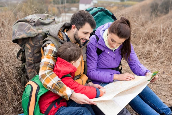 Familia con mochilas mirando el mapa - foto de stock