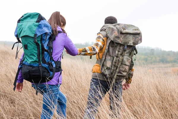 Young couple with backpacks walking in countryside — Stock Photo