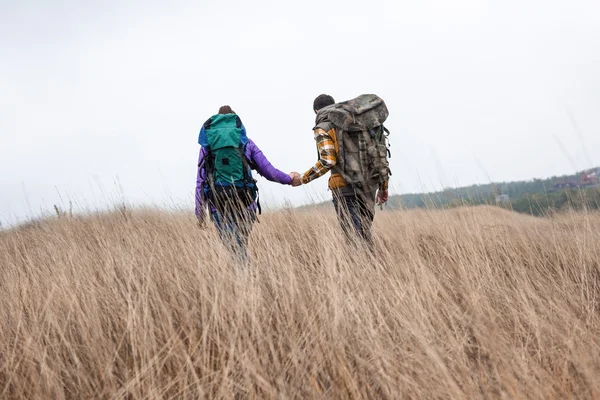Young couple with backpacks walking in countryside — Stock Photo