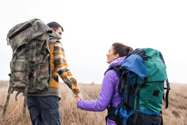 Young couple with backpacks holding hands — Stock Photo