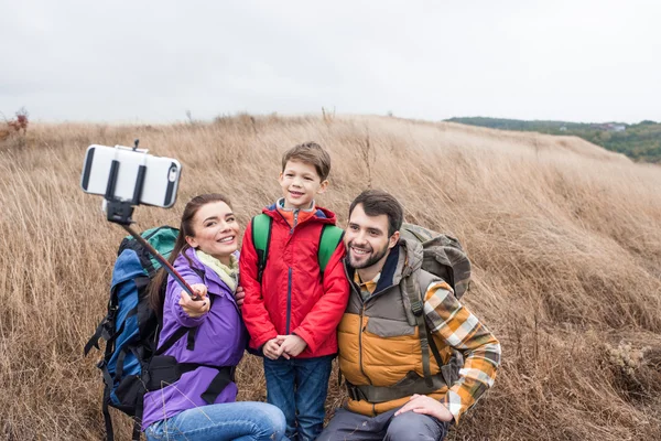 Familia feliz con mochilas tomando selfie - foto de stock