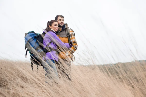 Young backpackers standing in dry grass — Stock Photo