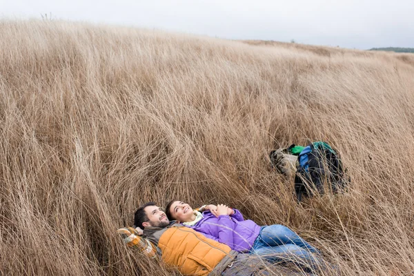 Heureux jeune couple allongé dans l'herbe — Photo de stock