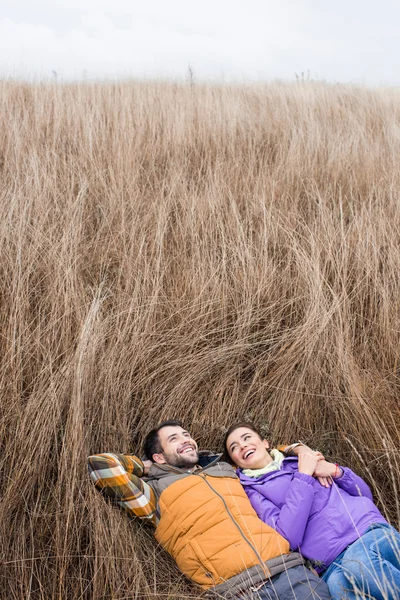 Heureux jeune couple allongé dans l'herbe — Photo de stock