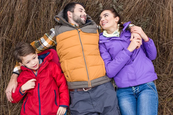 Familia sonriente abrazándose en la hierba - foto de stock