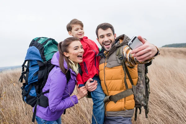 Familia feliz con mochilas tomando selfie - foto de stock