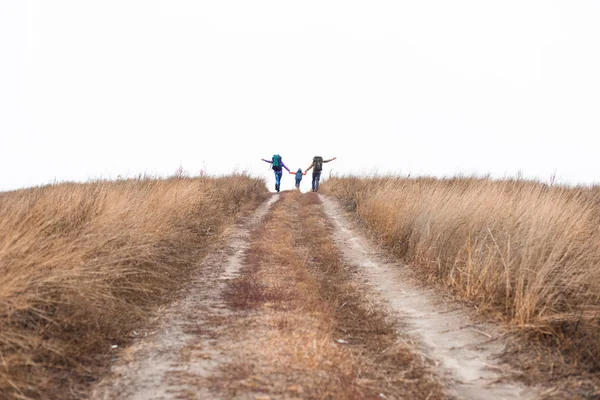 Família com mochilas correndo no caminho rural — Fotografia de Stock