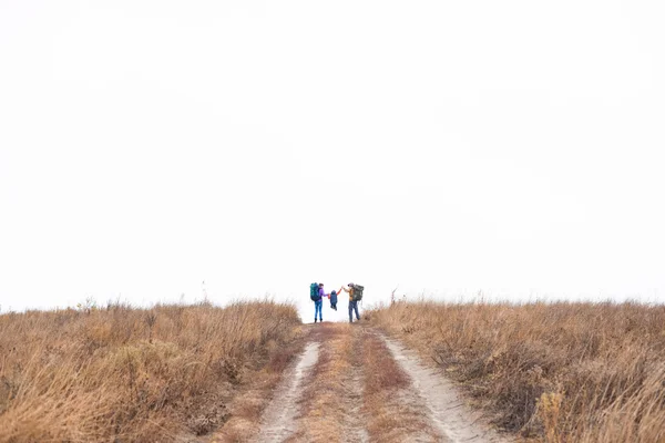 Family with backpacks running on rural path — Stock Photo