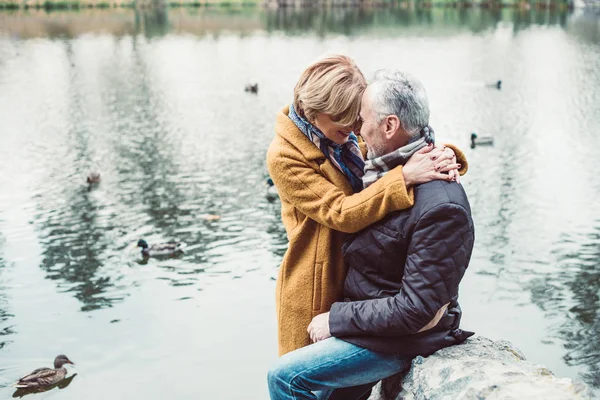 Счастливая взрослая пара обнимается у озера — стоковое фото