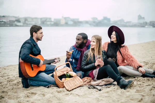 Счастливые молодые друзья с гитарой на пикнике — стоковое фото