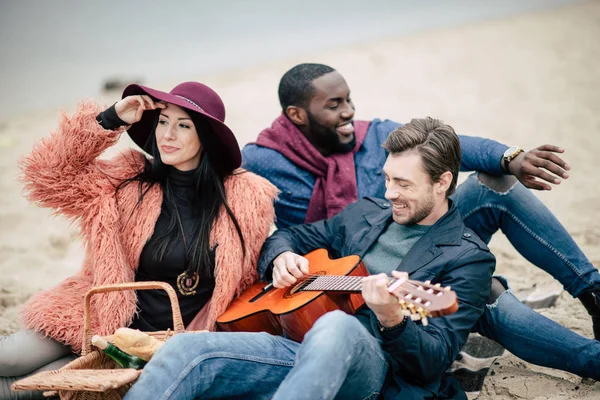 Amigos felices con la guitarra en el picnic - foto de stock