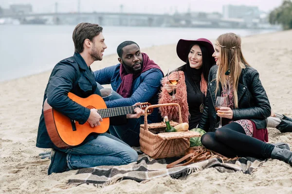 Happy friends with guitar at alfresco picnic — Stock Photo