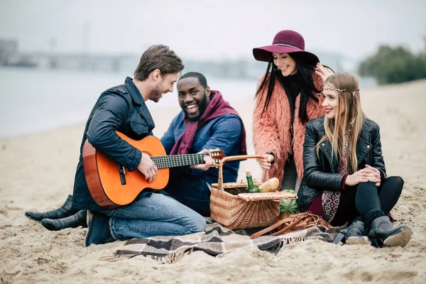 Счастливые друзья с гитарой на пикнике — стоковое фото