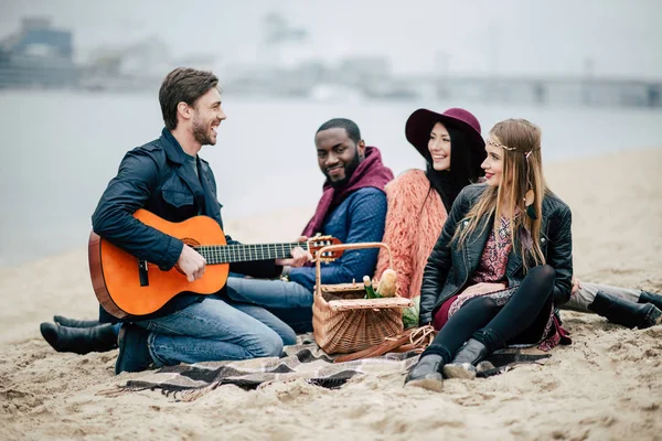 Happy friends with guitar at picnic — Stock Photo