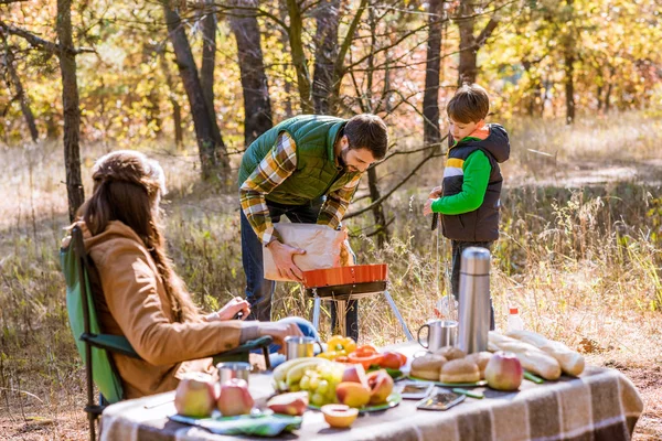 Father and son putting coals in grill — Stock Photo