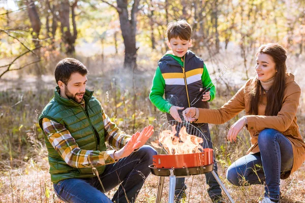 Familia feliz preparando barbacoa en el parque — Stock Photo