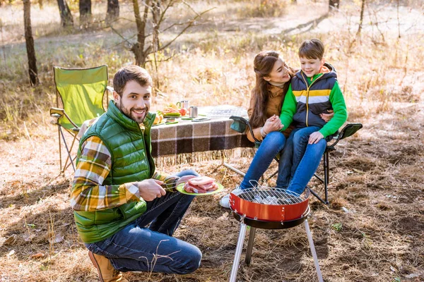 Family grilling meat on barbecue — Stock Photo