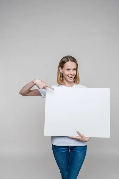 Mujer apuntando a tablero en blanco - foto de stock