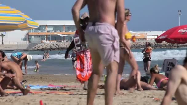 Praias espanholas na Catalunha. As pessoas tomam banho de sol na praia ao sol quente . — Vídeo de Stock