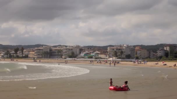 Los niños juegan, se bañan y descansan en la playa . — Vídeos de Stock