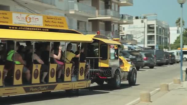 Stadens turisttåg med släp. Yachten är förankrad intill stranden. Spanska parkering för yachter i en landsortsstad Porto Cristo. Mallorca — Stockvideo